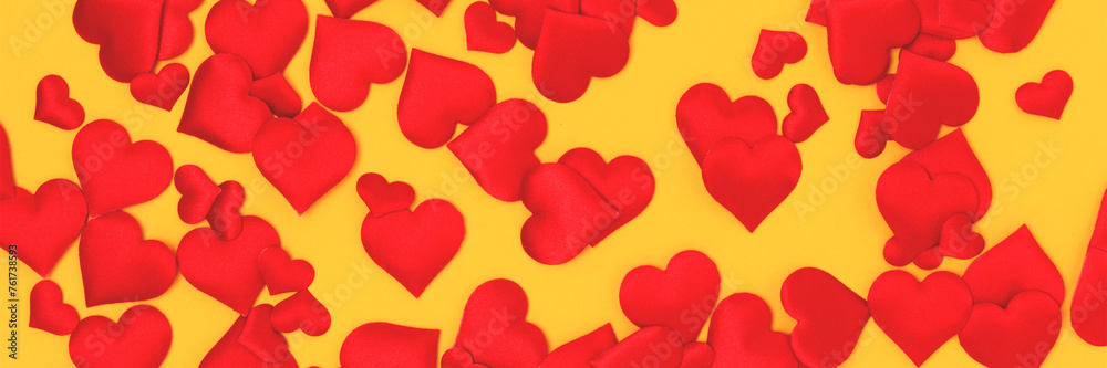 Banner with texture made of red confetti in a heart shape on a yellow background.