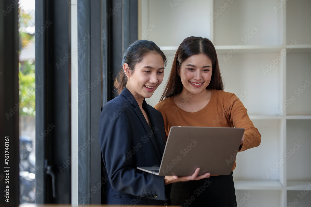 Two women are looking at a laptop together Two women are looking at a laptop together