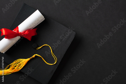Flat lay composition with graduation hat and diploma on black background. Top view.