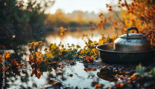  a tea pot sitting on top of a puddle of water next to a forest filled with green and yellow leaves.