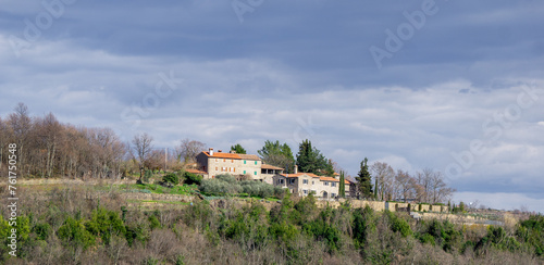 Several houses placed on a green hill in Istria on cloudy day © Rodrigo
