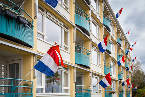 Dutch flags with an orange pennant on the facade of an apartment complex in the city of Deventer during King's Day photo