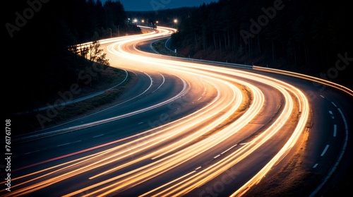 Bent road brightened by streaks of car lights during twilight 