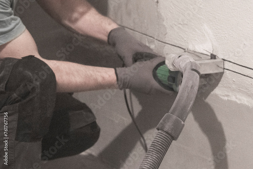 Worker Precision: Groove Cutting for Electrical Wiring Installation in Room.