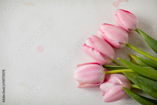 A bouquet of pink tulips and pink tinsel on a white background in the upper right corner. Copy space. View from above.