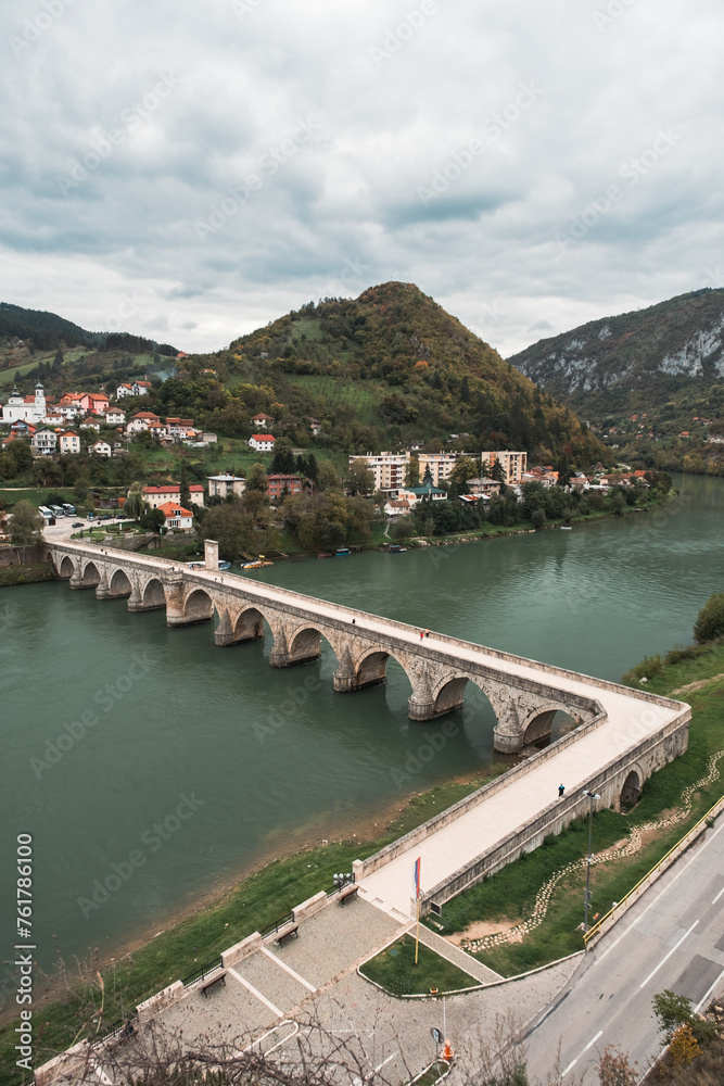 Vertical shot of old Ottoman type bridge on a river with hills in background, river Drina in Visegrad