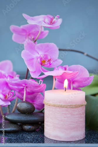 Spa background with pink orchid , candle and zen black stones on gray.