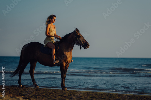 Side view of an equestrian riding a horse at the beach.