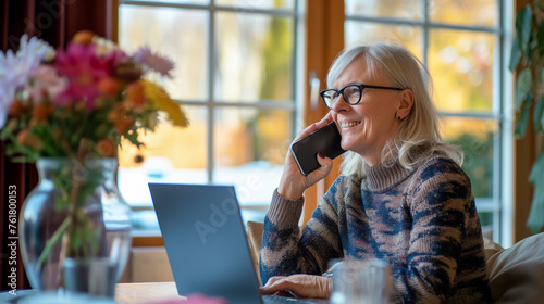 Portrait of a smiling woman talking on the phone, working as a freelancer, senior European businesswoman working in a cafe