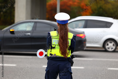 Policjantka ruchu drogowego z lizakiem podczas zatrzymania pojazdów na drodze z tarczą do zatrzymywania. 