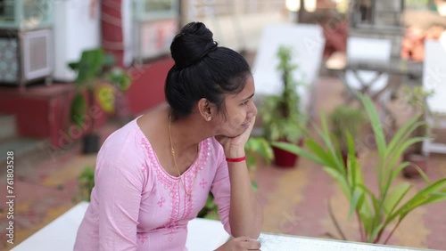 Thoughtful sad young Indian ethnic woman, sitting at table in afternoon on street. Sadness. 