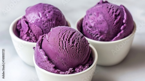 three bowls filled with purple ice cream on top of a white counter top next to a white bowl with three scoops of ice cream.