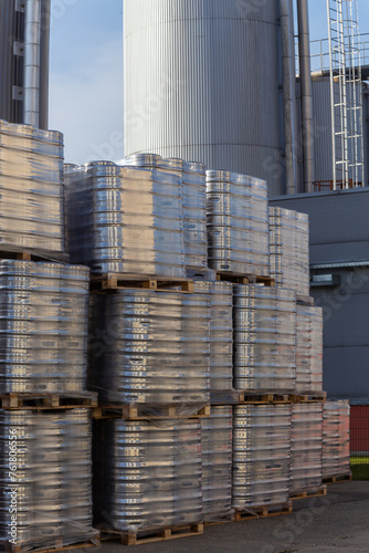 Large amount of aluminium beer kegs stacked on each other with euro palettes and wrapped around with vinyl foil.