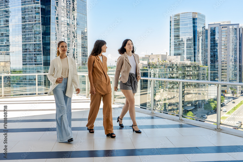 Three businesswomen walking on a tower building terrace