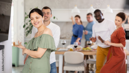 Merry male and female friends enjoying lively dance during small gathering at close friends