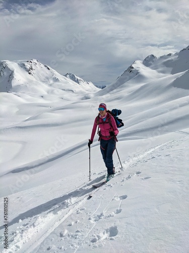 Ski tourer on the climb to the summit. Woman on the move in the mountains. Ski mountaineering in Davos Switzerland. High quality photo.