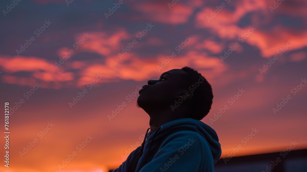 The silhouette of a young person against a richly hued sunset sky, conveys a feeling of youthful hope The silhouette of a young person against a richly hued sunset sky, conveys a feeling of youthful hope