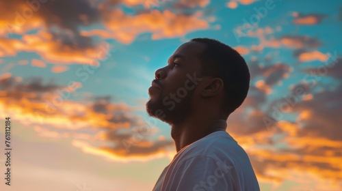 A serene profile of a man silhouetted against softly lit sunset clouds in the sky speaks of tranquility