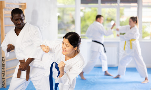 Woman and man in pairs exercising karate movements during group training