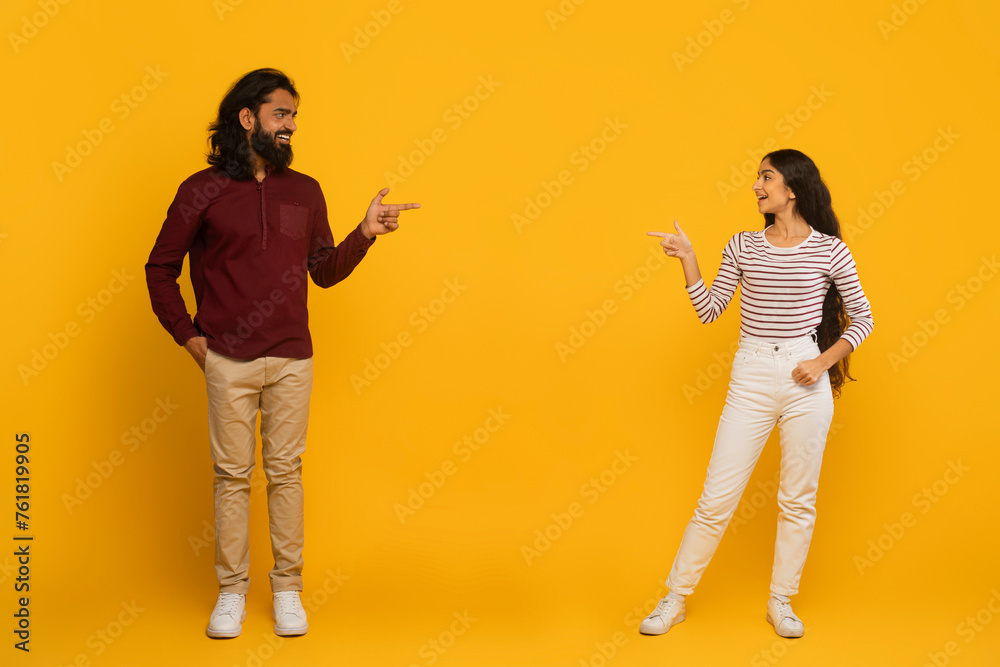 Fototapeta premium Man and woman pointing each other on yellow background