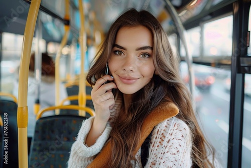 A charming young woman talks on the phone in a bus, with a friendly smile and urban background
