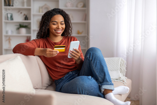 Mobile Banking. Smiling Black Female Using Smartphone And Credit Card At Home