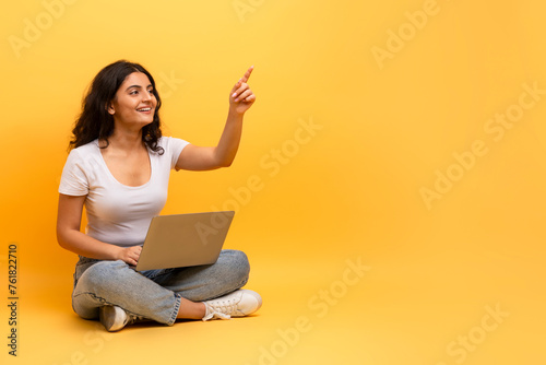 Enthusiastic woman pointing while using laptop photo