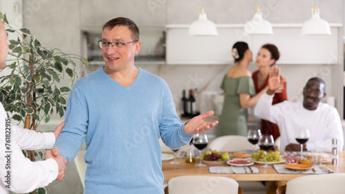 Two men shaking hands when meeting in kitchen at home