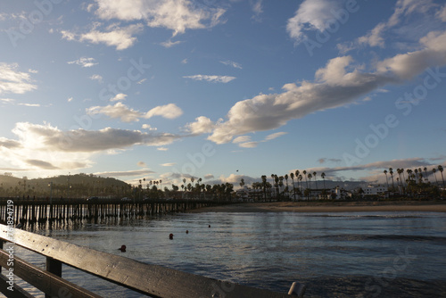 Looking over Stearns Wharf in Santa Barbara, California at sunset with clouds and palm trees.