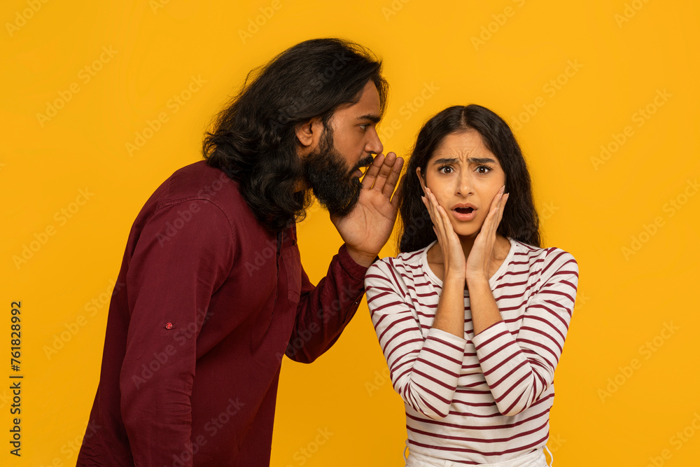 Man whispers secret to surprised woman on yellow Man whispers secret to surprised woman on yellow