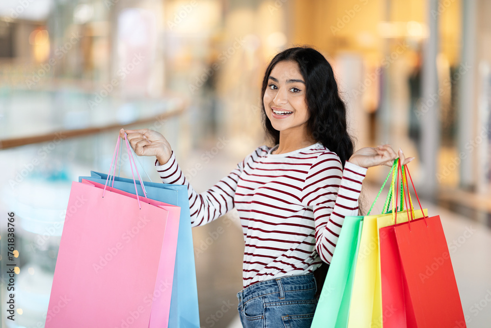Joyful young eastern woman showing her purchases Joyful young eastern woman showing her purchases