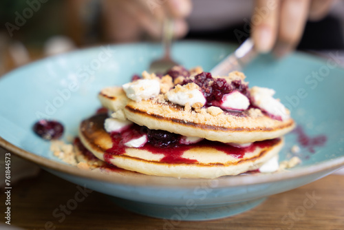 Fotografie Close-up of pancakes with berry compote and cream on a blue plate