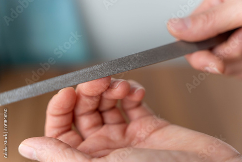Close-up of woman undergoing nail filing in professional manicure