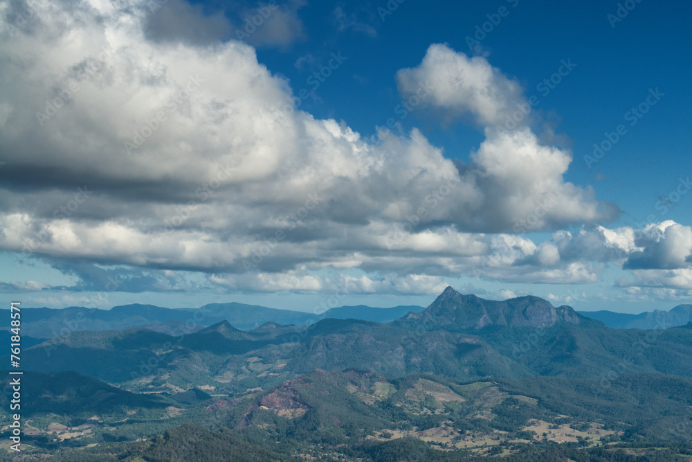 From Springbrook NP, Queensland, a stunning vista reveals Mount Warning amid lush rainforest, misty valleys, and distant horizons