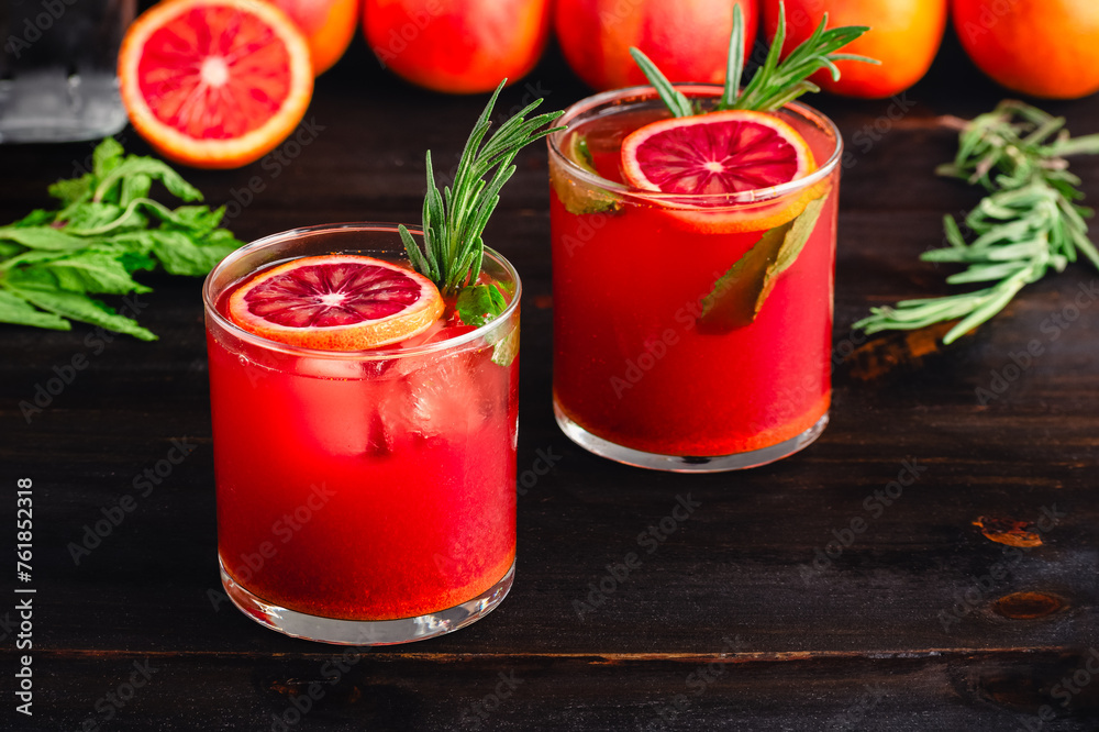 Sparkling Blood Orange Mocktails Garnished with Fresh Herbs: Mocktails with citrus juice, ginger, turmeric, rosemary, and mint in rocks glasses Sparkling Blood Orange Mocktails Garnished with Fresh Herbs: Mocktails with citrus juice, ginger, turmeric, rosemary, and mint in rocks glasses