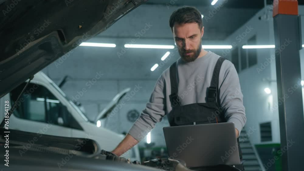 Caucasian adult man worker auto mechanic repairing car problem of engine using laptop managing computer system checking detail maintenance automotive diagnostics in automobile garage service station