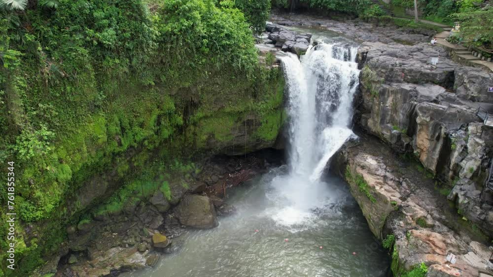 Backward reveal aerial shot of Tegenungan Waterfall on sunny day. Bali, Indonesia. Backward reveal aerial shot of Tegenungan Waterfall on sunny day. Bali, Indonesia.
