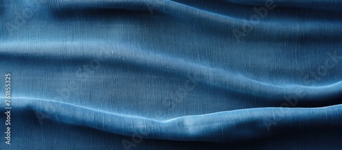 A close up of a satin sleeve in electric blue with wavelike patterns, resembling the movement of water under a grey sky filled with fluffy clouds