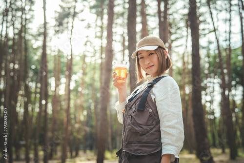 キャンプ場でビールを飲む女性キャンパー（お酒・アルコール・クラフトビール・発泡酒） 
