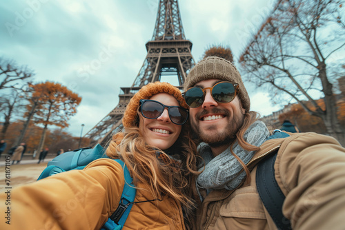 Young Couple with beanies and sunglasses taking selfie  in Front of Eiffel Tower at winter time.