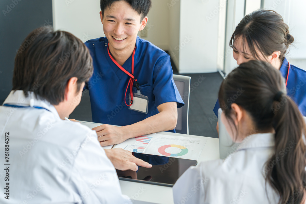 Obraz premium 医局でカンファレンス・打ち合わせ・ミーティングする男女の看護師・技師・作業療法士・理学療法士・医師 