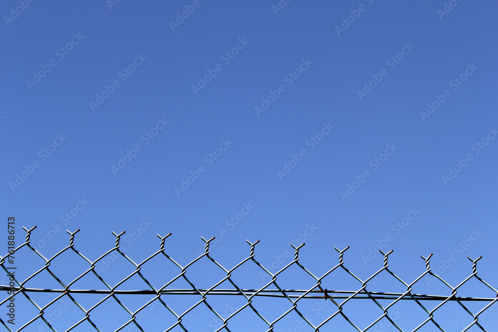 Chain-link fence against a blue sky background Chain-link fence against a blue sky background