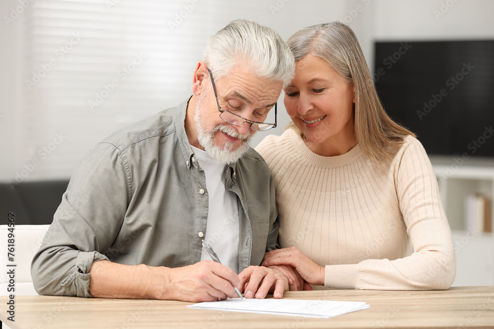 Senior couple signing Last Will and Testament indoors