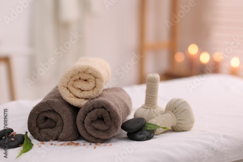 Spa stones, rolled towels and herbal bags on massage table indoors