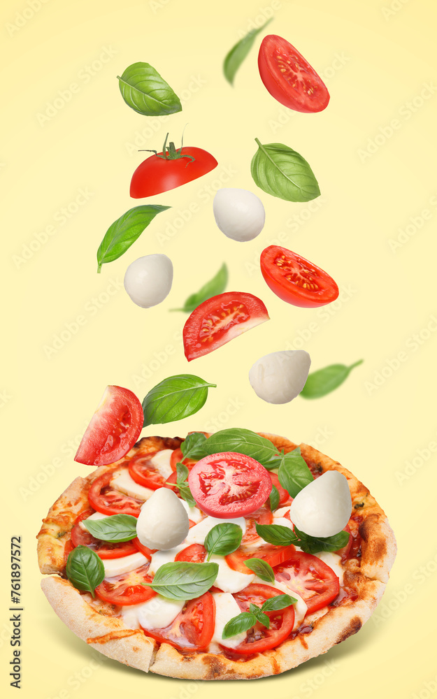 Caprese pizza and ingredients in air on pale yellow background