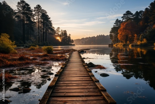 Wooden pier over lake with trees at sunset, reflecting sky and clouds in water