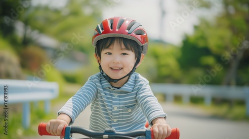 Asian cute little boy having fun by riding bicycle. Cute kid in safety helmet biking outdoors.