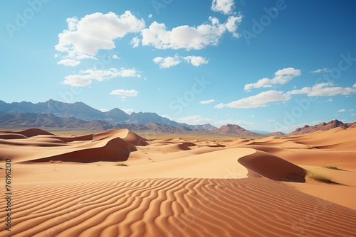 Sand dunes in the desert with mountains on the horizon and a clear blue sky
