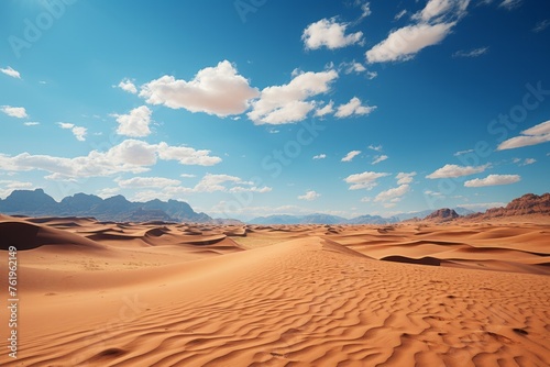 Desert landscape with mountains  dunes  and cumulus clouds against a blue sky