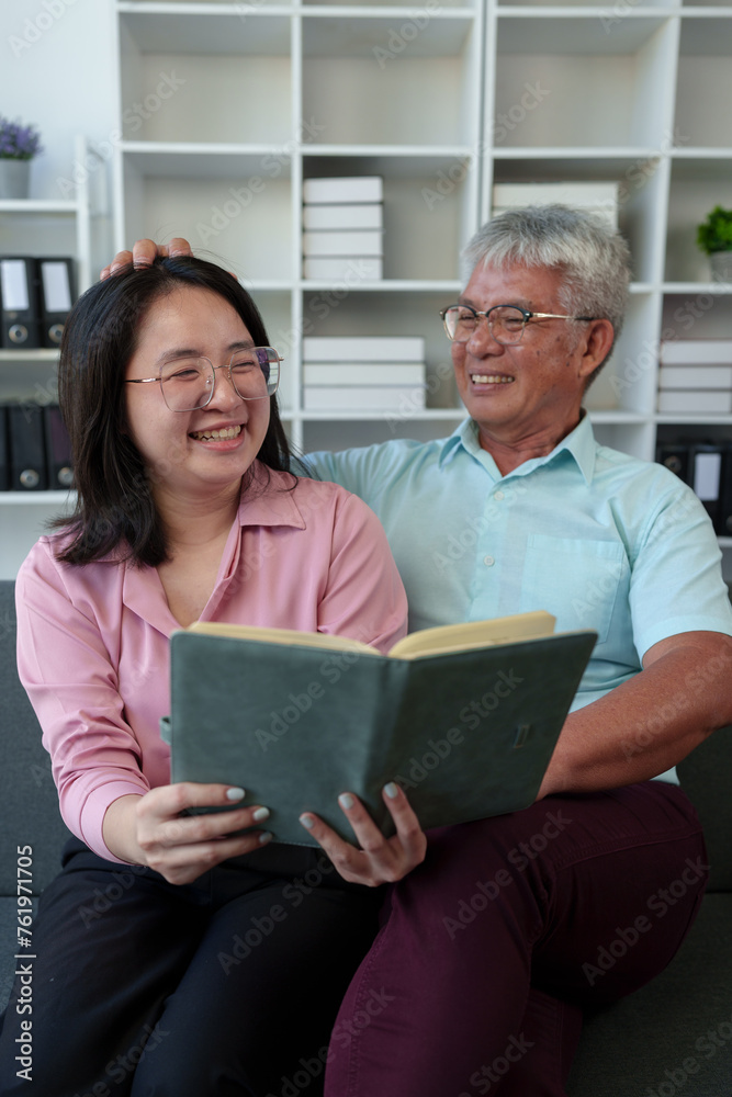 Surprised Asian woman hugs elderly father Teasing in various verses Reading in the living room holidays family relationships Holiday celebration Father's Day and elderly people's health care concept. Surprised Asian woman hugs elderly father Teasing in various verses Reading in the living room holidays family relationships Holiday celebration Father's Day and elderly people's health care concept.